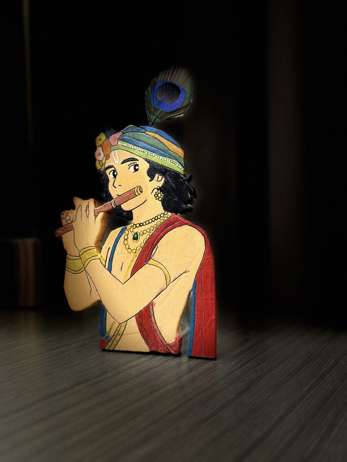 Side profile view of handcrafted wooden Krishna figurine showing carved depth and painted details