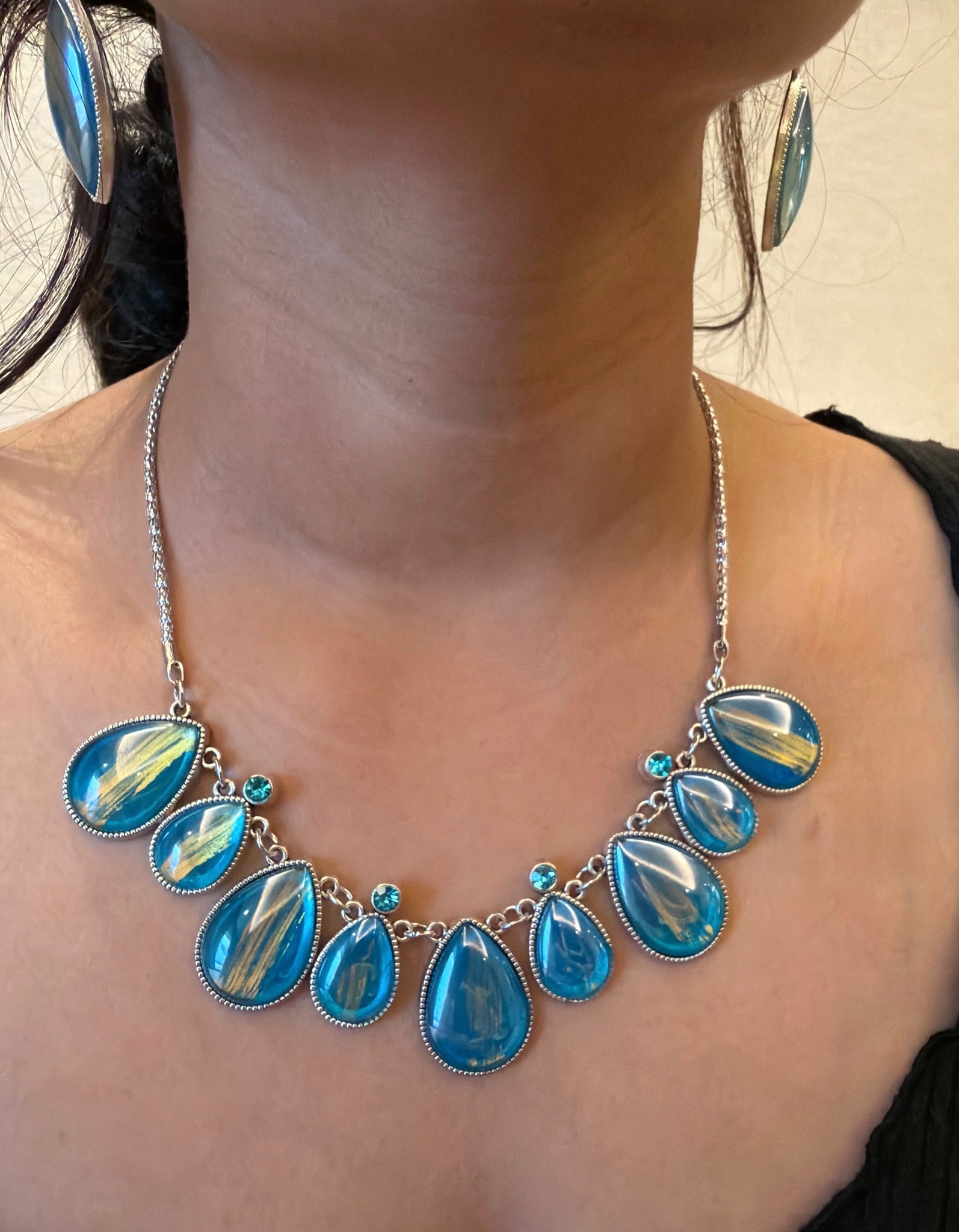 Santorini blue and gold statement necklace and earring set styled on surface