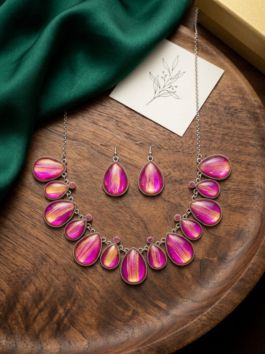 Pink and gold statement necklace with matching drop earrings on white background