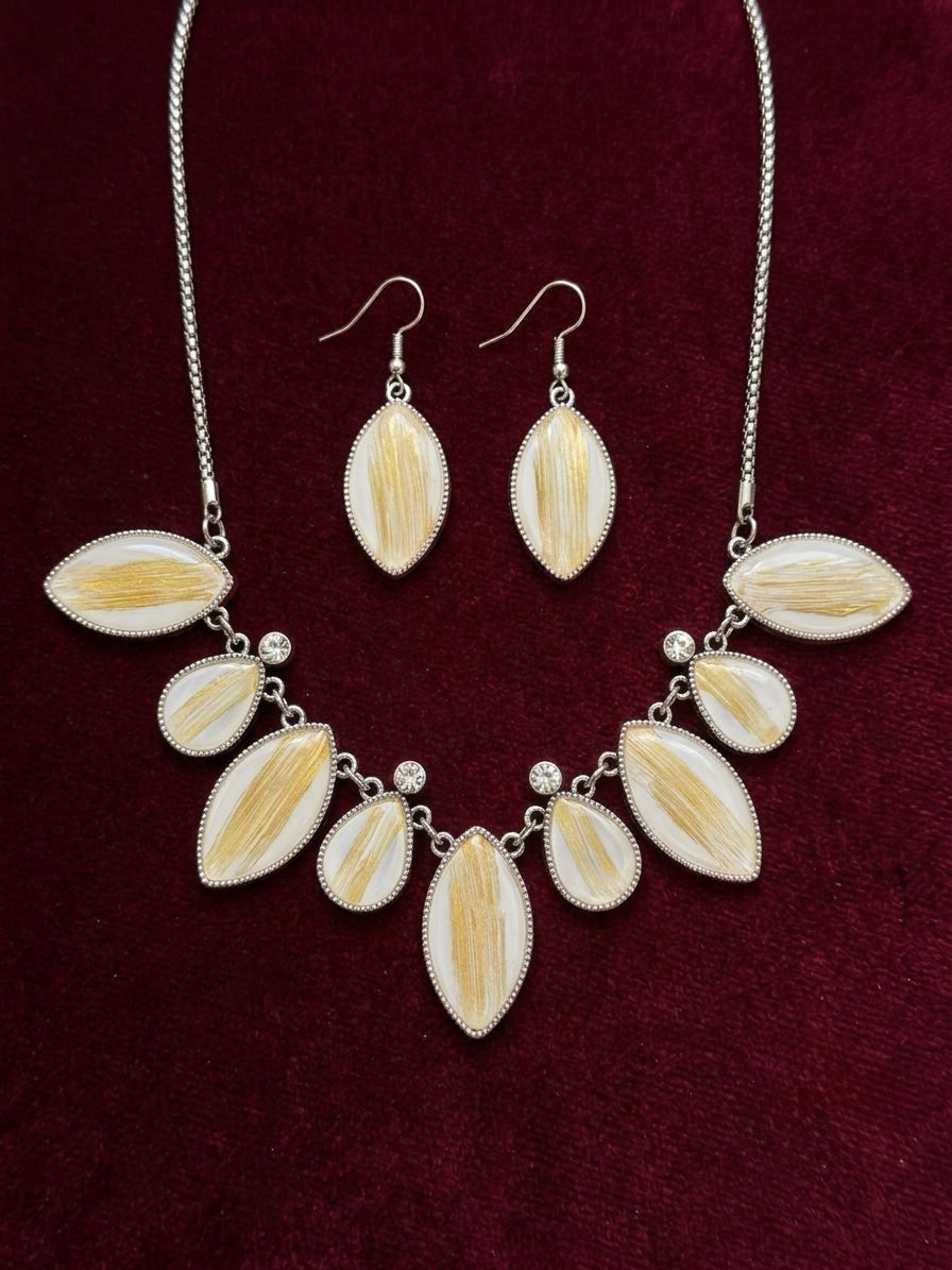 Mykonos white and gold teardrop necklace and earring set on burgundy velvet background